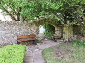 A garden with stone walls and benches at The Columbine in Akeld near Wooler