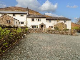 A house with a stone wall and gravel driveway at Two Town End in Mungrisdale, Mosedale
