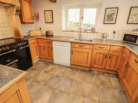 A kitchen with wooden cabinets and appliances at Two Town End in Mungrisdale, Mosedale