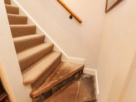 A staircase with carpet and a wooden handrail at Two Town End in Mungrisdale, Mosedale