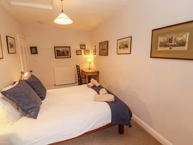 A bedroom with a bed, table, and wall art at Two Town End, Mungrisdale, Mosedale