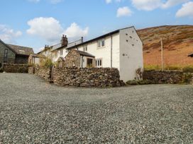 A house with a stone wall and gravel driveway at Two Town End in Mungrisdale, Mosedale