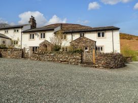 A house with a gravel driveway and stone wall at Two Town End in Mungrisdale, Mosedale