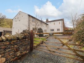 A gate in front of a house surrounded by trees at Two Town End in Mungrisdale, Mosedale