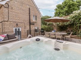 An outdoor area with a hot tub and dining set at The Stable House in Sherborne
