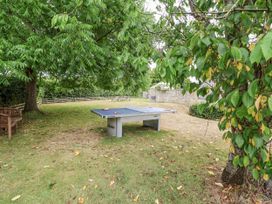 A garden with a ping pong table and a bench at The Stable House in Sherborne
