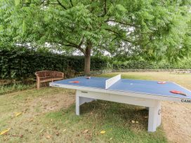 A table tennis setup under a tree with a bench at The Stable House in Sherborne