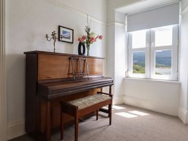 A music room with a piano and bench at 5 Porkington Terrace in Barmouth