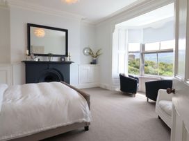 A bedroom with a bed, fireplace, mirror, and two armchairs at 5 Porkington Terrace, Barmouth