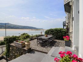An outdoor patio with a table and chairs overlooking a bay at 5 Porkington Terrace in Barmouth