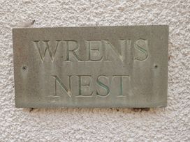 A sign displaying the name WREN'S NEST at Wrens Nest in Slapton