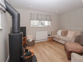 A snug with a wood stove and sofa at Wrens Nest in Slapton