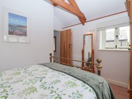 A bedroom with a bed and a mirror at Wrens Nest in Slapton
