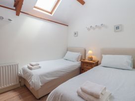 A bedroom with two beds and a bedside table at Wrens Nest in Slapton