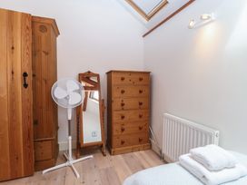 A bedroom with a wardrobe, fan, mirror, chest of drawers at Wrens Nest in Slapton