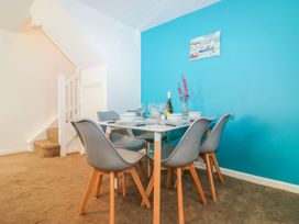 A dining area with a table and six chairs set with bowls and glasses near a staircase at Broadsands Paignton