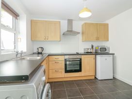 A kitchen with wooden cabinets a built-in oven a microwave a toaster a kettle a washing machine and a refrigerator at Broadsands in Paignton