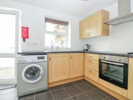 A kitchen with wooden cabinets a washing machine an oven a kettle and a window at Broadsands in Paignton