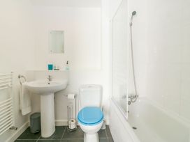 A bathroom with a pedestal sink a toilet with a blue seat a bathtub with a shower at Broadsands in Paignton