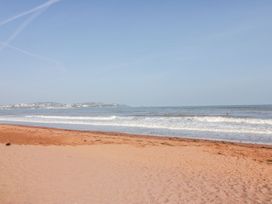 A sandy beach with waves and a distant coastal town at Broadsands in Paignton