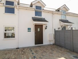 Exterior view of white terraced houses with wooden doors and small overhangs at Broadsands in Paignton