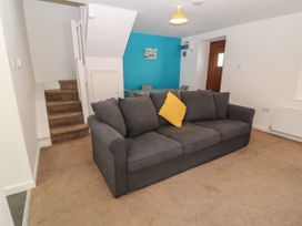 A living room with a gray sofa and yellow pillow near stairs and a dining area with blue wall at Broadsands in Paignton