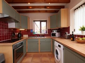 A kitchen with cabinets, stove, microwave, and washing machine at Scoresby Cottage @ Summerfield Farm, Hawsker