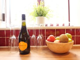 A kitchen with a bottle of prosecco and a fruit bowl at Scoresby Cottage @ Summerfield Farm, Hawsker