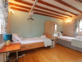 A bedroom with two beds and a wardrobe at Scoresby Cottage @ Summerfield Farm, Hawsker