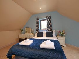 A bedroom with a bed and side table at Scoresby Cottage @ Summerfield Farm in Hawsker