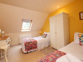 A bedroom with two beds and a wardrobe at Scoresby Cottage @ Summerfield Farm, Hawsker
