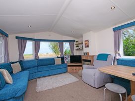 A living room with a sofa, armchair, and television at Abbey View @ Summerfield Farm, Hawsker