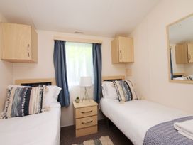 A bedroom with two single beds and a bedside table at Abbey View @ Summerfield Farm, Hawsker