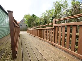 A decking area with a handrail and pathway at Abbey View @ Summerfield Farm Hawsker