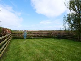 A garden with a chair and umbrella stand at Abbey View @ Summerfield Farm in Hawsker