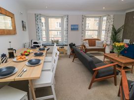 A living room featuring a dining table with chairs and a sofa at Still Waters in Swanage