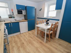A kitchen with appliances and dining table at Still Waters in Swanage