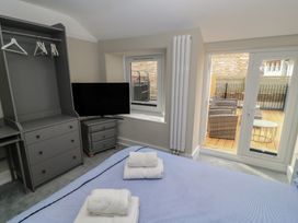 A bedroom with a bed, television, and outdoor seating at Still Waters in Swanage