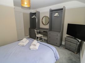 A bedroom with a bed, wardrobe, desk, and television at Still Waters in Swanage