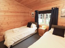 A bedroom with two beds and a nightstand at The Fold Number 28, Burnside Park near Keswick
