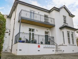 A white two-story building with balconies and potted plants at Apartment 4 10 Somers Court in Paignton