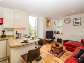 A living room with a red sofa a small wooden coffee table and a television near the window at Apartment 4 10 Somers Court in Paignton