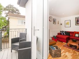 A balcony with two black wicker chairs and a living room with a red sectional sofa and framed pictures on the walls at Apartment 4 10 Somers Court in Paignton