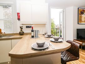 A kitchen island set with grey bowls plates and glasses next to a window and balcony door at Apartment 4 10 Somers Court in Paignton