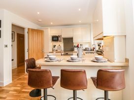 A kitchen with a countertop set for four with bowls and glasses and three brown bar stools at Apartment 4 10 Somers Court in Paignton