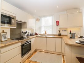 A kitchen with white cabinets wooden countertops a sink under a window and built in oven at Apartment 4 10 Somers Court in Paignton