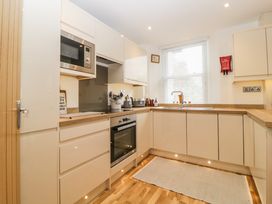 A kitchen with white cabinets wooden countertops and a window with blinds at Apartment 4 10 Somers Court in Paignton