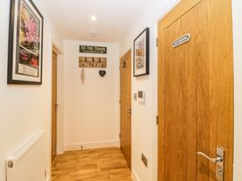 A hallway with light wood doors two framed pictures a coat rack with decorations and a radiator at Apartment 4 10 Somers Court in Paignton