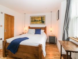 A bedroom with a wooden bed and blue pillows near a window with gray curtains at Apartment 4 10 Somers Court in Paignton