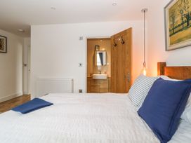A bedroom with a bed with blue pillows a wooden door leading to a bathroom and a hanging light at Apartment 4 10 Somers Court in Paignton